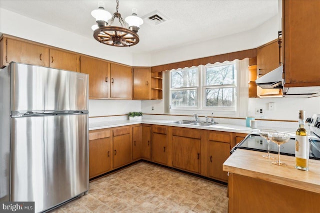 kitchen with light countertops, a sink, freestanding refrigerator, and visible vents