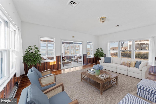 living room featuring visible vents, wood finished floors, and a healthy amount of sunlight