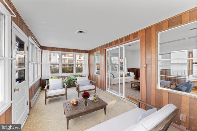 sunroom / solarium featuring visible vents, a baseboard heating unit, wooden walls, and carpet