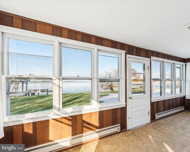 unfurnished sunroom featuring a baseboard radiator, plenty of natural light, and a water view