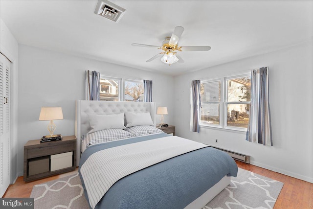 bedroom featuring wood finished floors, visible vents, a ceiling fan, and baseboards