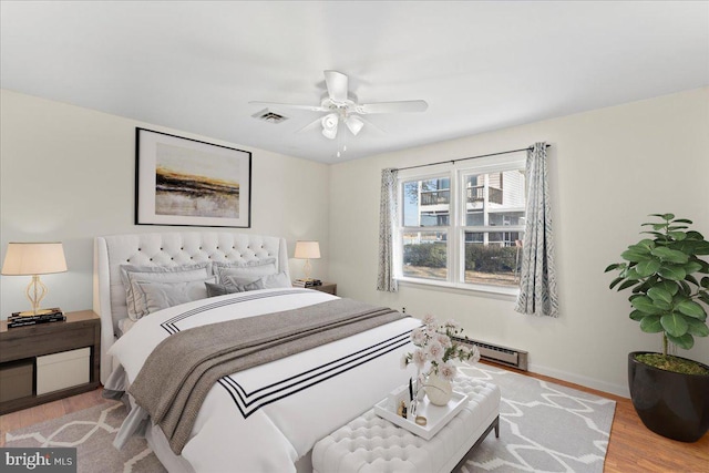 bedroom featuring ceiling fan, visible vents, baseboards, wood finished floors, and a baseboard radiator