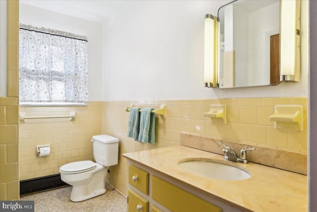 bathroom featuring tile patterned flooring, tile walls, a wainscoted wall, toilet, and vanity