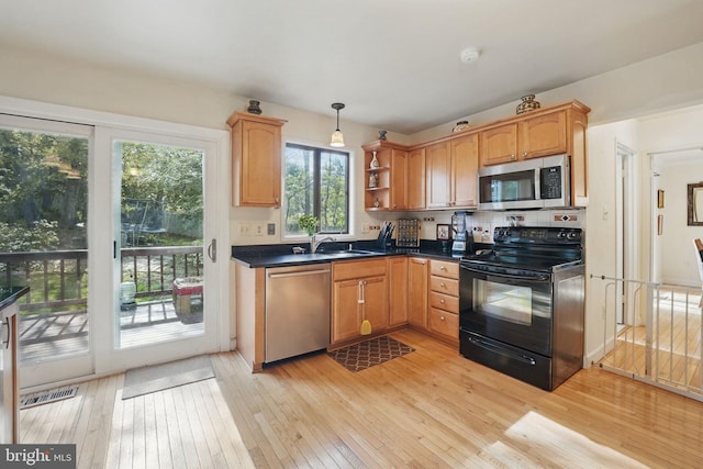 9601 Tinsmith Ln, Burke, VA 22015 - kitchen featuring open shelves, pendant lighting, dark countertops, light wood-style floors, and appliances with stainless steel finishes