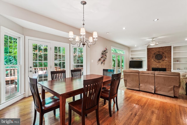 dining space featuring recessed lighting, a fireplace, built in features, light wood-type flooring, and ceiling fan with notable chandelier