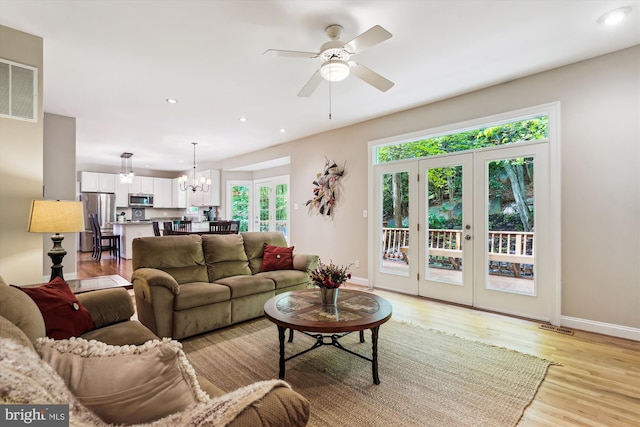 living room featuring recessed lighting, light wood-style floors, visible vents, baseboards, and ceiling fan with notable chandelier