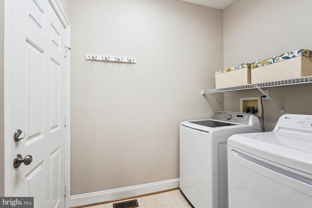 washroom featuring separate washer and dryer, visible vents, laundry area, and baseboards