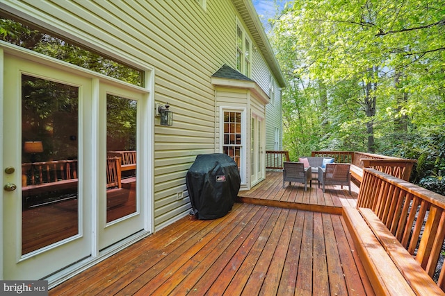wooden terrace with an outdoor living space and grilling area