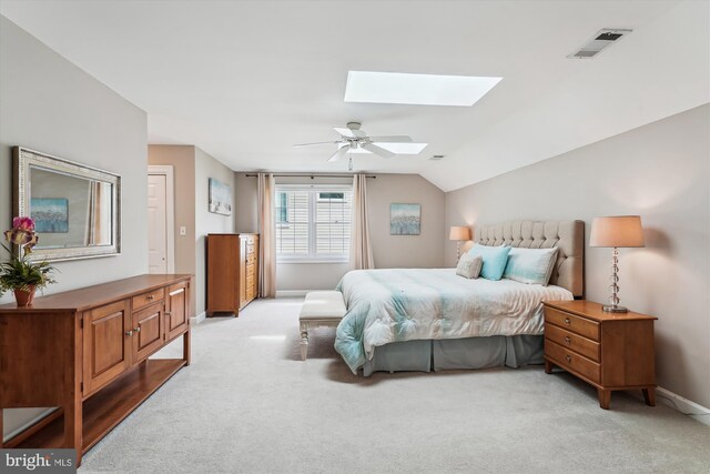 bedroom with vaulted ceiling with skylight, light carpet, baseboards, visible vents, and a ceiling fan