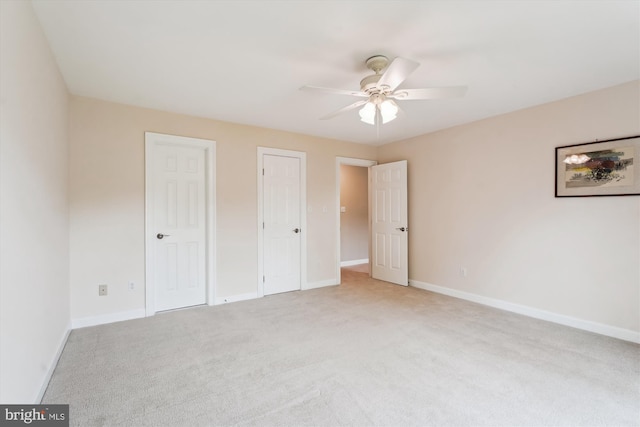unfurnished bedroom featuring baseboards, light carpet, two closets, and ceiling fan