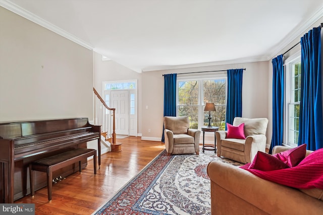 living area with stairway, wood finished floors, crown molding, and baseboards