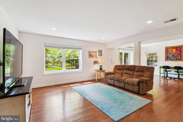 living area featuring visible vents, wood finished floors, and a healthy amount of sunlight