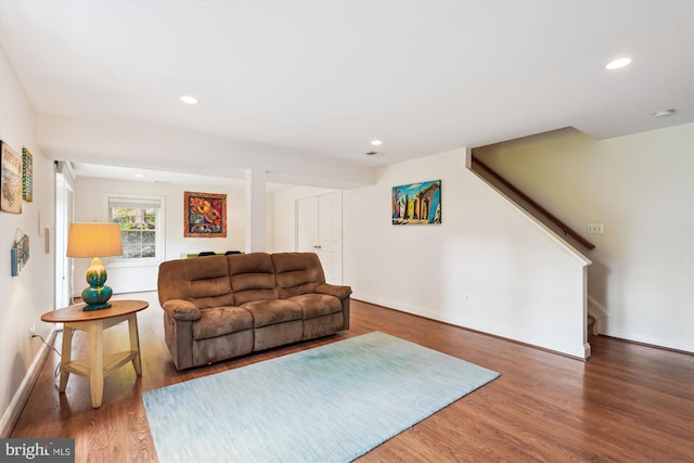 living room featuring baseboards, stairway, wood finished floors, and recessed lighting