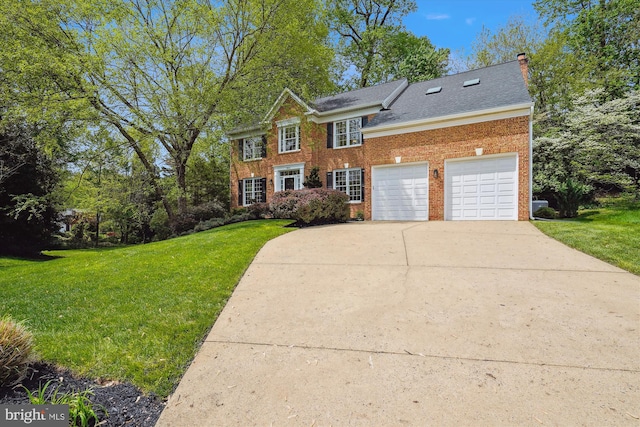 colonial inspired home featuring a chimney, brick siding, a front yard, and driveway