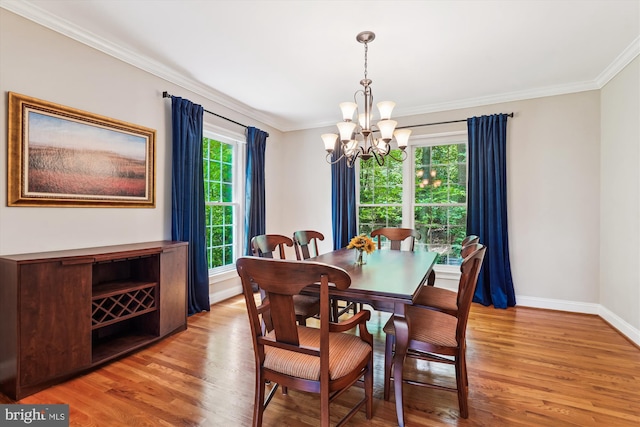 dining space featuring baseboards, ornamental molding, an inviting chandelier, and light wood-style flooring