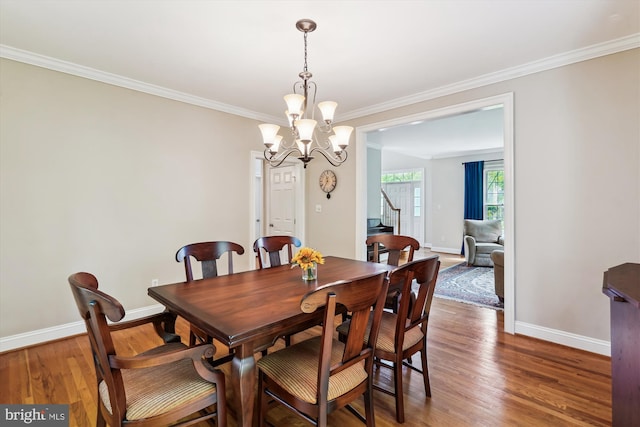 dining space featuring stairway, a chandelier, baseboards, ornamental molding, and wood finished floors