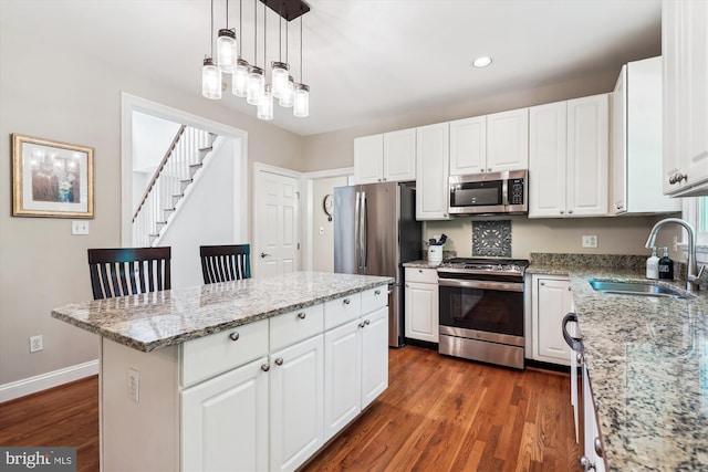 kitchen featuring recessed lighting, stainless steel appliances, a sink, a center island, and dark wood-type flooring