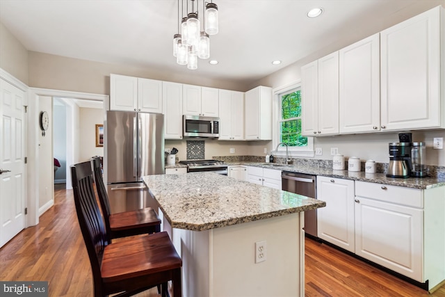 kitchen with recessed lighting, a sink, stainless steel appliances, a center island, and white cabinetry
