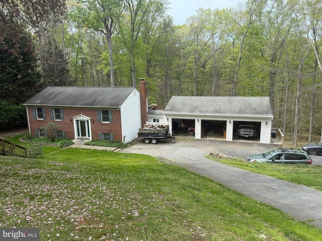 view of front of house with a detached garage, a chimney, a front lawn, and an outbuilding