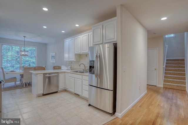 kitchen featuring appliances with stainless steel finishes, a peninsula, recessed lighting, a sink, and baseboards