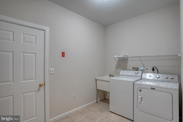 laundry area with washing machine and clothes dryer, baseboards, and light tile patterned floors