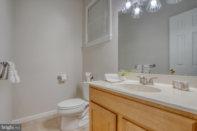 half bathroom featuring tile patterned floors, toilet, vanity, and baseboards