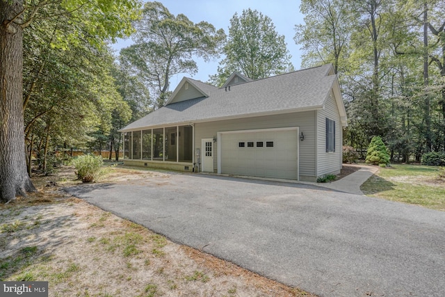 view of property exterior with driveway, a sunroom, an attached garage, and roof with shingles