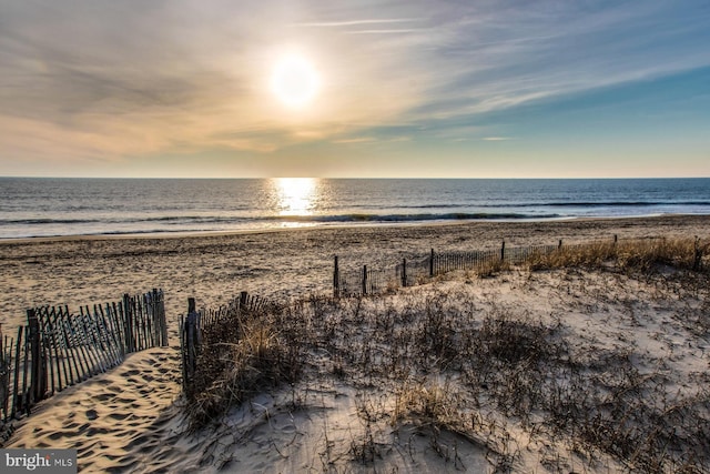 water view featuring nearby beach and fence