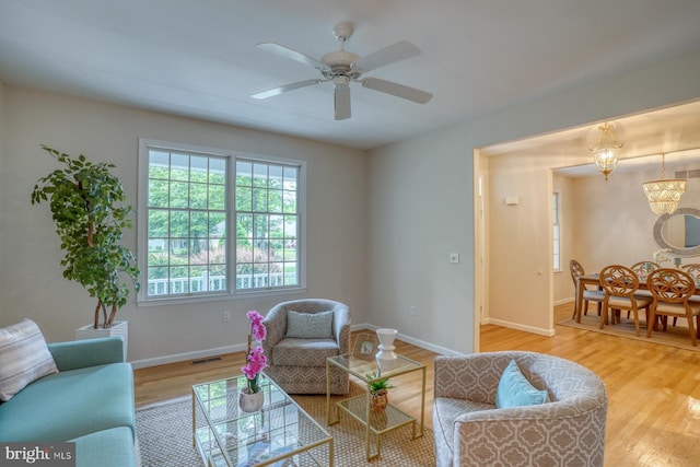 living room featuring wood finished floors, baseboards, and ceiling fan
