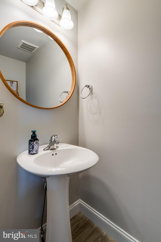 bathroom with baseboards, visible vents, and wood finished floors