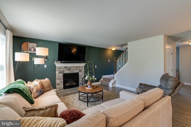 living area featuring baseboards, a fireplace, stairs, and wood finished floors