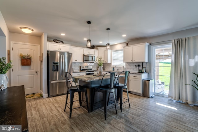 kitchen with decorative backsplash, light wood-type flooring, white cabinets, dark stone counters, and stainless steel appliances