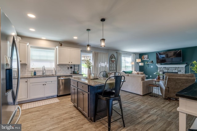 kitchen with a sink, light wood finished floors, a kitchen breakfast bar, and stainless steel appliances