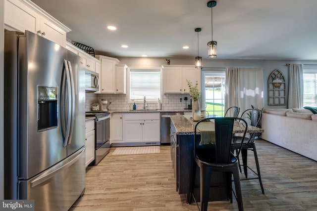kitchen with a breakfast bar, a sink, plenty of natural light, dark stone counters, and stainless steel appliances