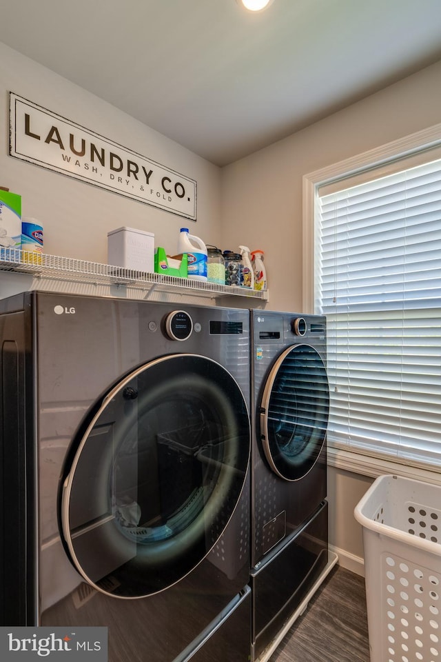 clothes washing area with separate washer and dryer, baseboards, laundry area, and wood finished floors