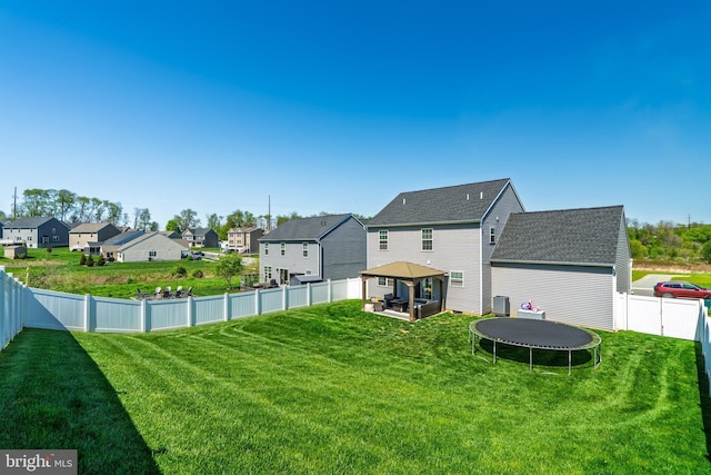 view of yard with a trampoline, a residential view, a gazebo, cooling unit, and a fenced backyard