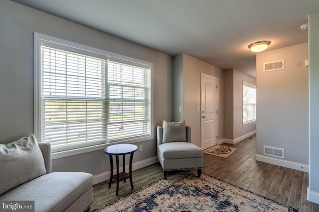 living area featuring visible vents, baseboards, and wood finished floors