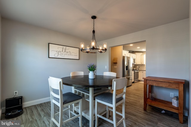 dining space featuring baseboards, a notable chandelier, and wood finished floors