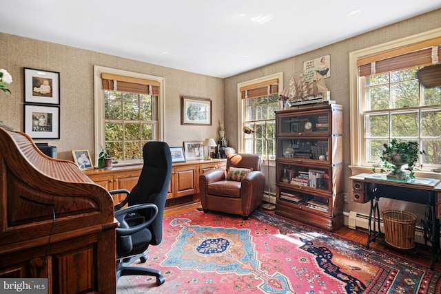office featuring wood finished floors, wallpapered walls, and a baseboard heating unit