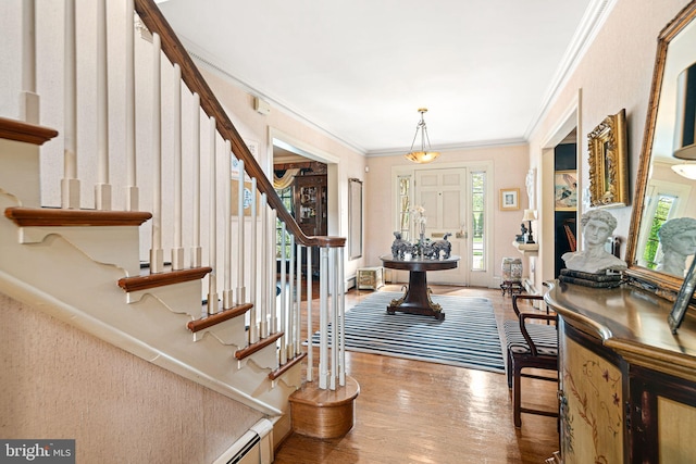 entryway with wood finished floors, stairs, and crown molding