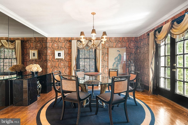 dining space with a chandelier, wallpapered walls, and ornamental molding