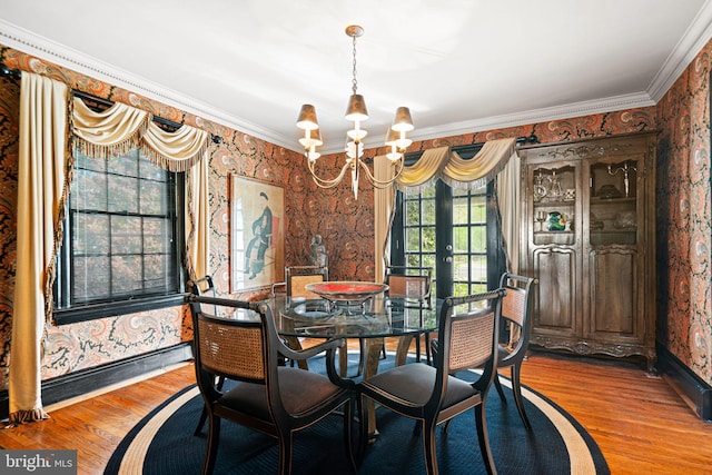 dining area with wallpapered walls, a chandelier, crown molding, light wood-type flooring, and french doors