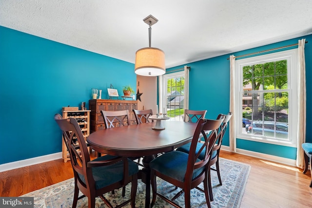 dining area featuring baseboards, a textured ceiling, and wood finished floors