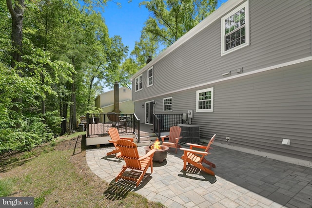 rear view of property with a patio, cooling unit, a wooden deck, and an outdoor fire pit