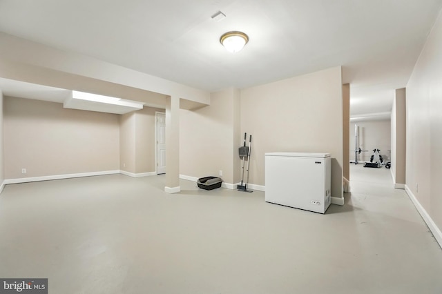 finished basement featuring baseboards and refrigerator