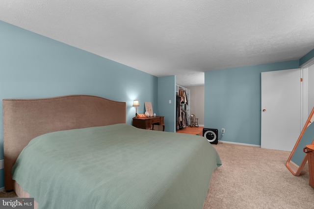 carpeted bedroom with a walk in closet, a closet, and a textured ceiling