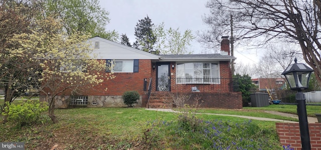 view of front facade featuring brick siding, a front yard, and a chimney