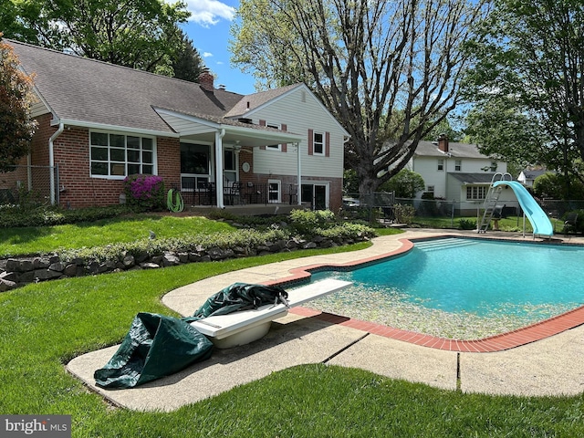 view of pool featuring a water slide, fence, a fenced in pool, and a yard