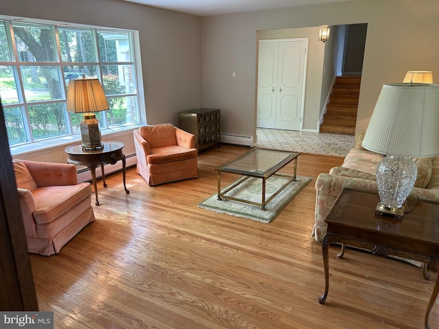 living area featuring stairway, wood finished floors, and a baseboard heating unit