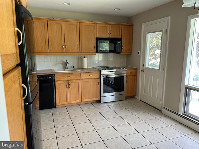 kitchen with a sink, brown cabinetry, black appliances, backsplash, and light countertops